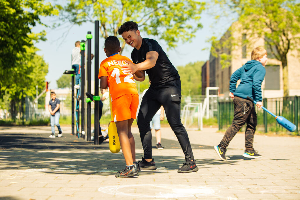 Ludios sportinstructeur verzorgt een gymles voor basisschoolleerlingen buiten op het schoolplein
